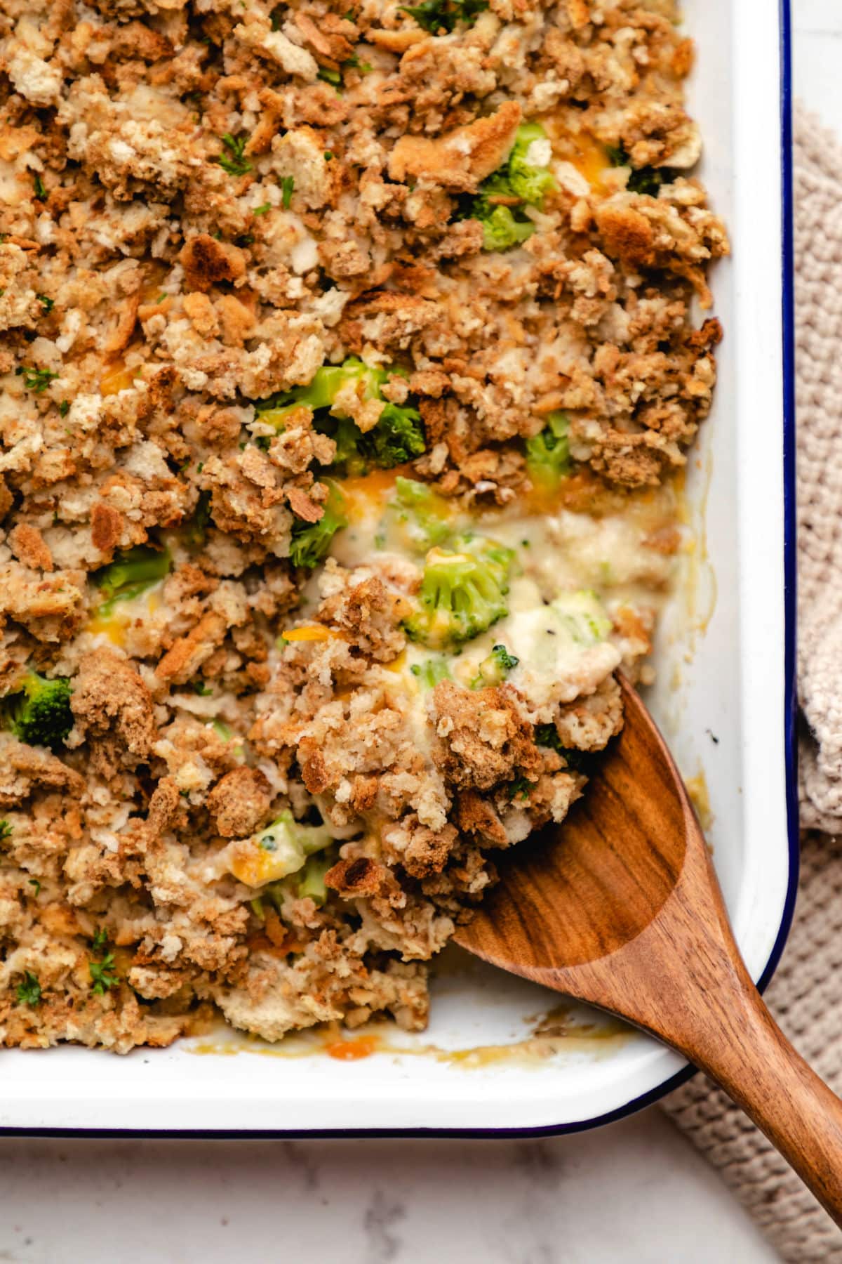 A wooden spoon scooping up chicken broccoli stuffing casserole.