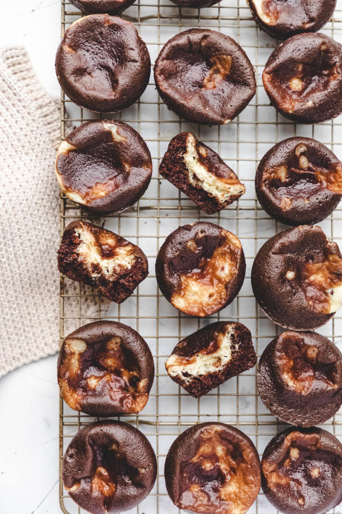 Three rows of chocolate cheesecake cupcakes next to a knit napkin.