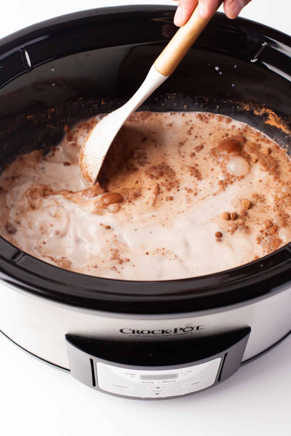 A spoon mixing cocoa powder into milk mixture.