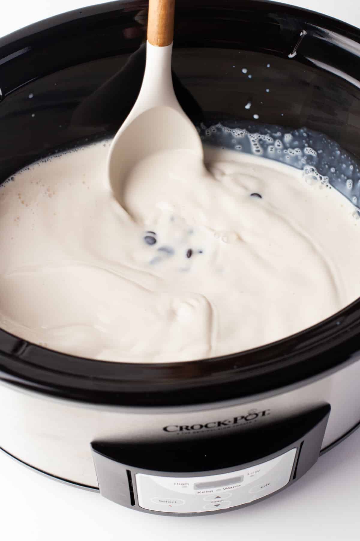 A spoon mixing chocolate chips into milk mixture. 