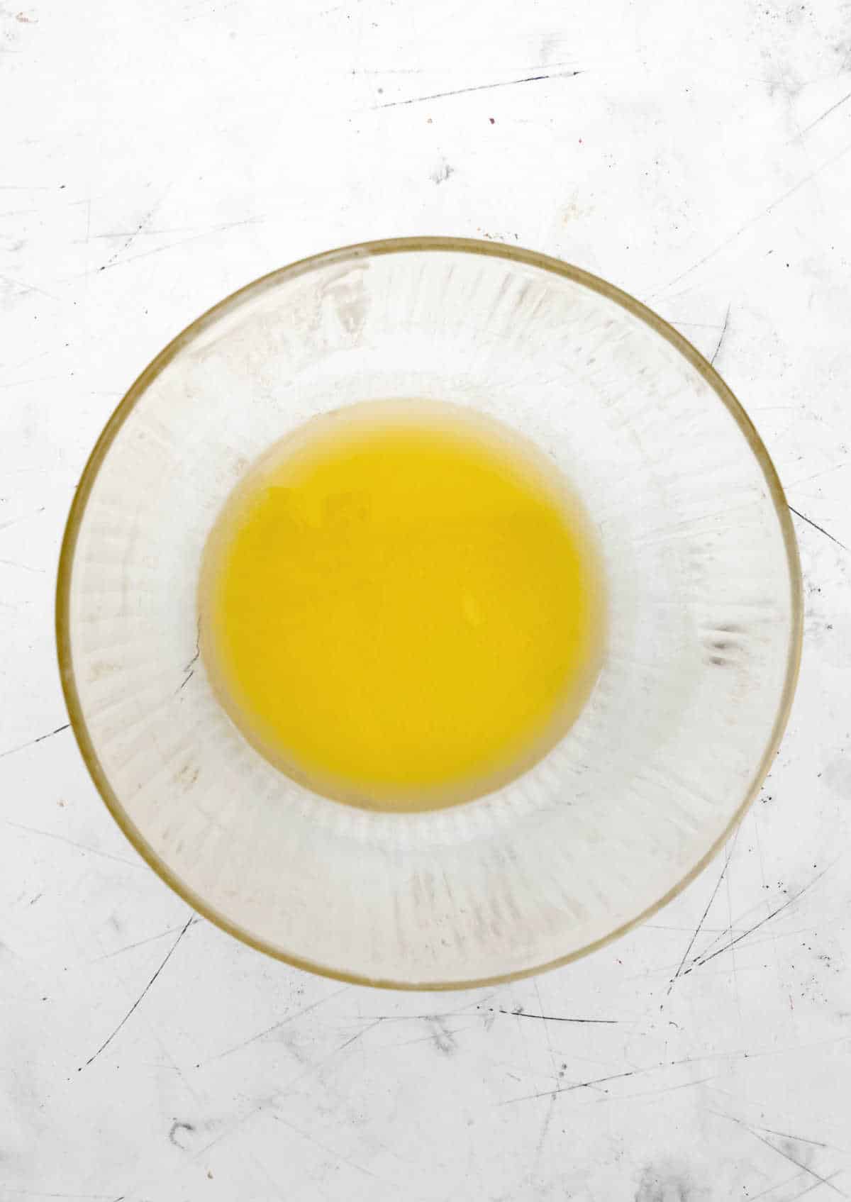 Melted butter in a large glass mixing bowl.