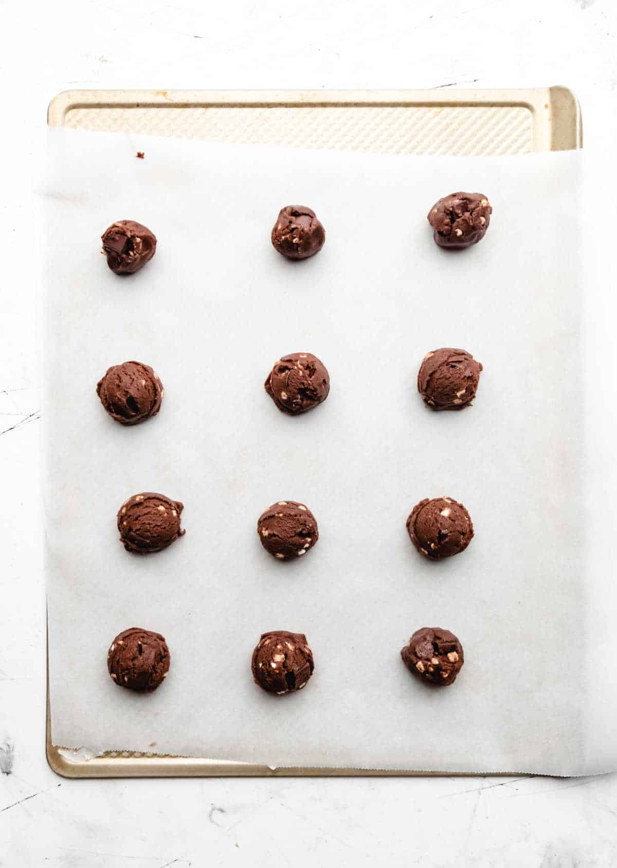 Hot chocolate cookie dough on a parchment lined baking sheet.