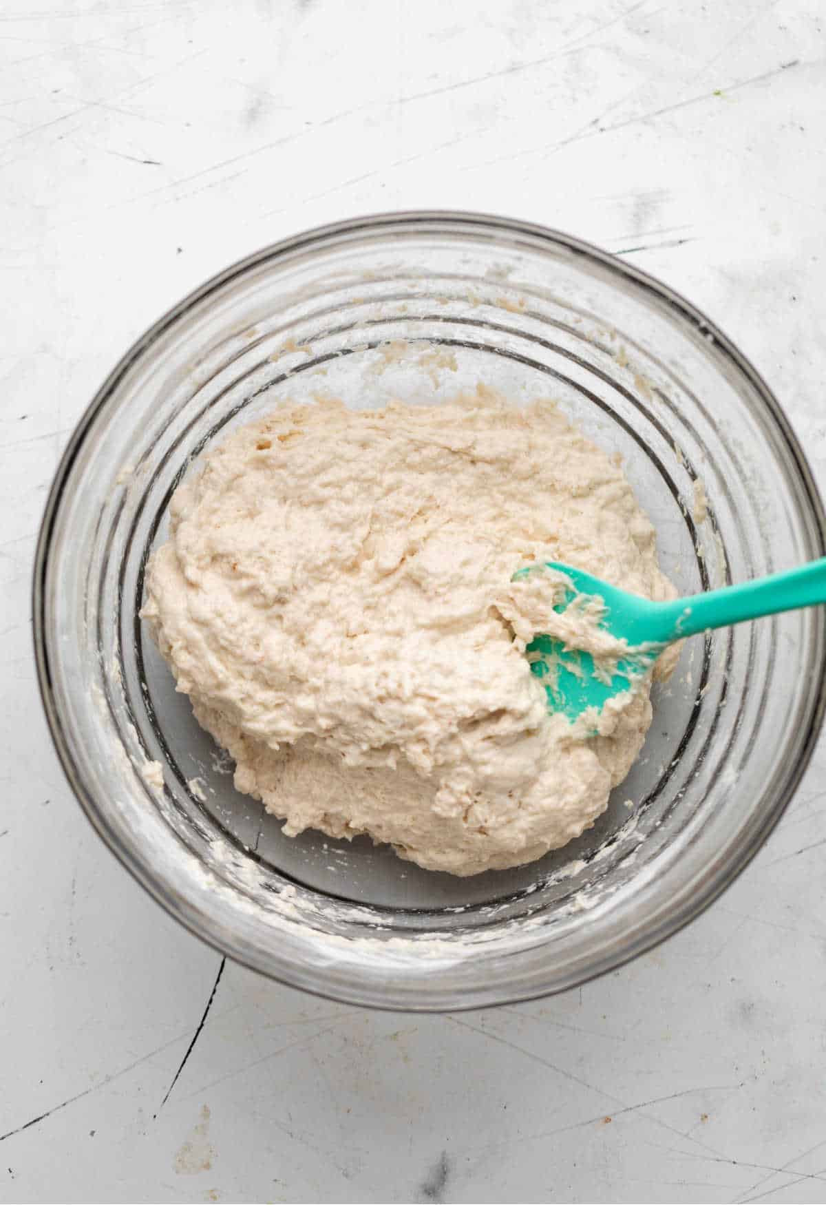 Flour yeast water cinnamon and water in a glass mixing bowl. 