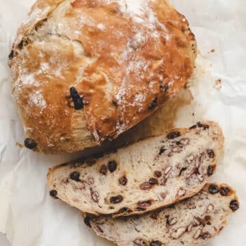 A loaf of no knead raisin bread with two slices cut.