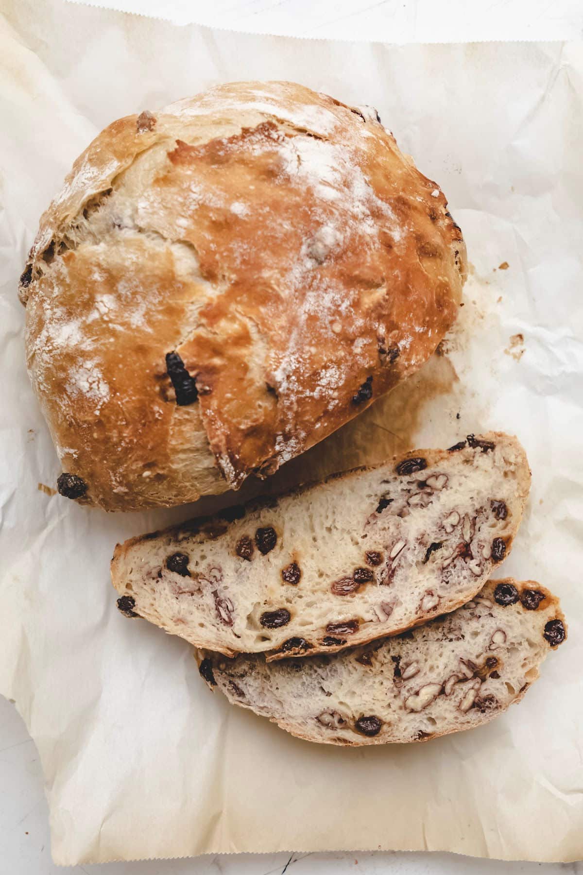 A loaf of no knead cinnamon raisin bread with two slices cut.