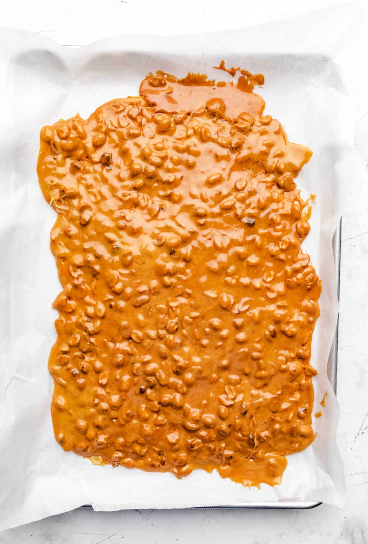 Peanut brittle mixture spread on a parchment lined pan.