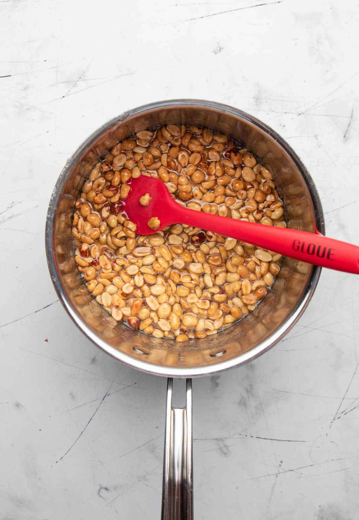 Peanuts in corn syrup mixture in a saucepan.