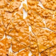 Broken pieces of peanut brittle on a piece of parchment paper.