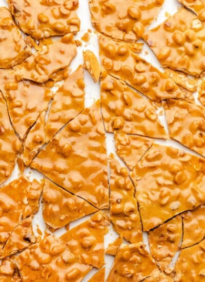 Broken pieces of peanut brittle on a piece of parchment paper.