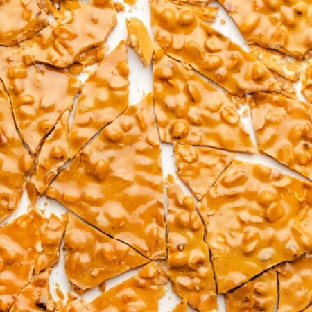 Broken pieces of peanut brittle on a piece of parchment paper.