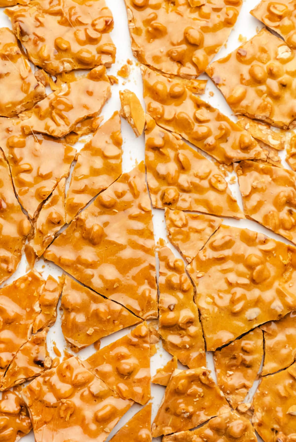 Broken pieces of peanut brittle on a piece of parchment paper. 