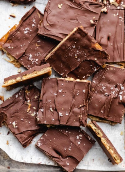 Pieces of saltine toffee on white parchment paper.