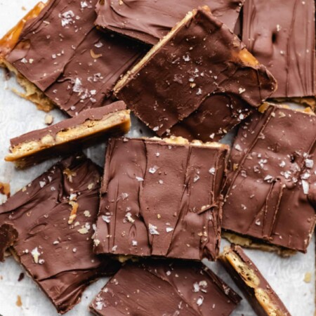 Pieces of saltine toffee on white parchment paper.