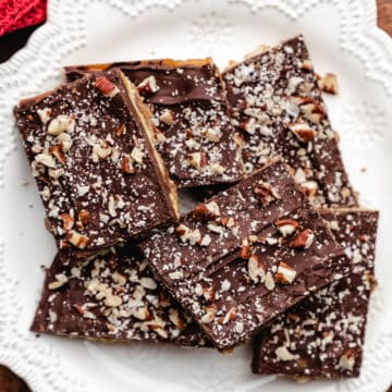 Pieces of saltine toffee on a white plate.