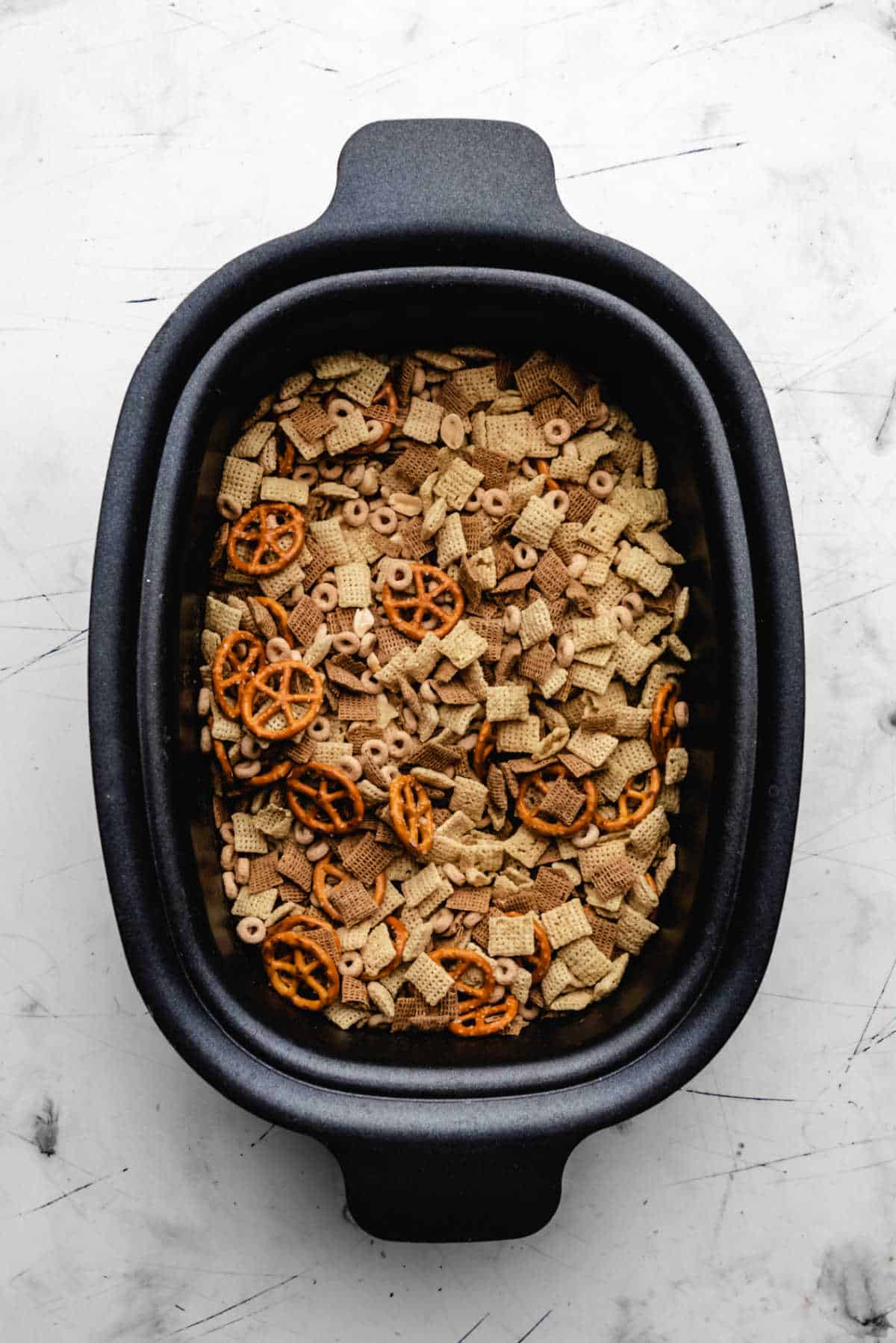 Butter mixture poured over cereal mixture in a slow cooker.