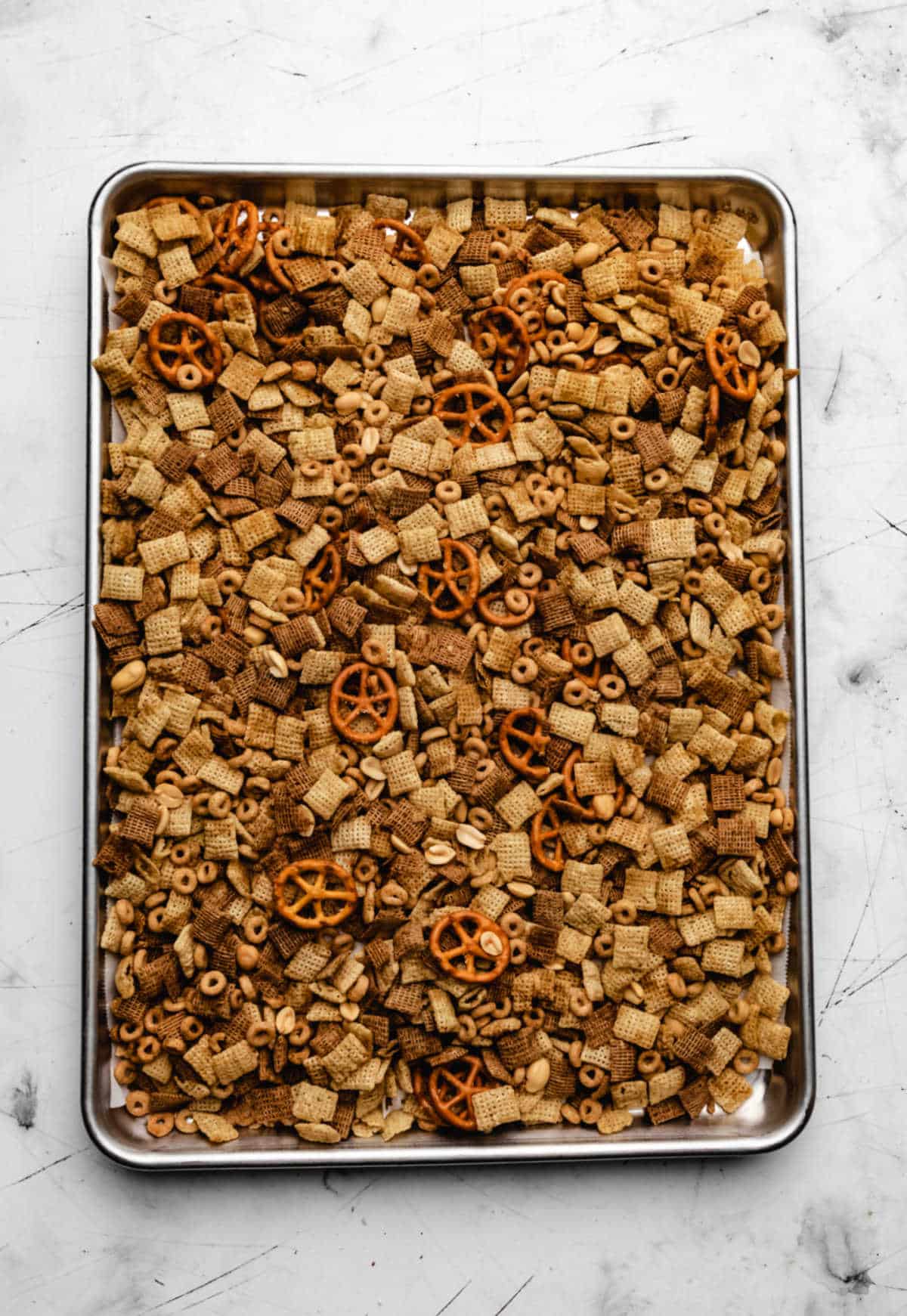 Slow cooker Chex mix spread out on a baking tray.
