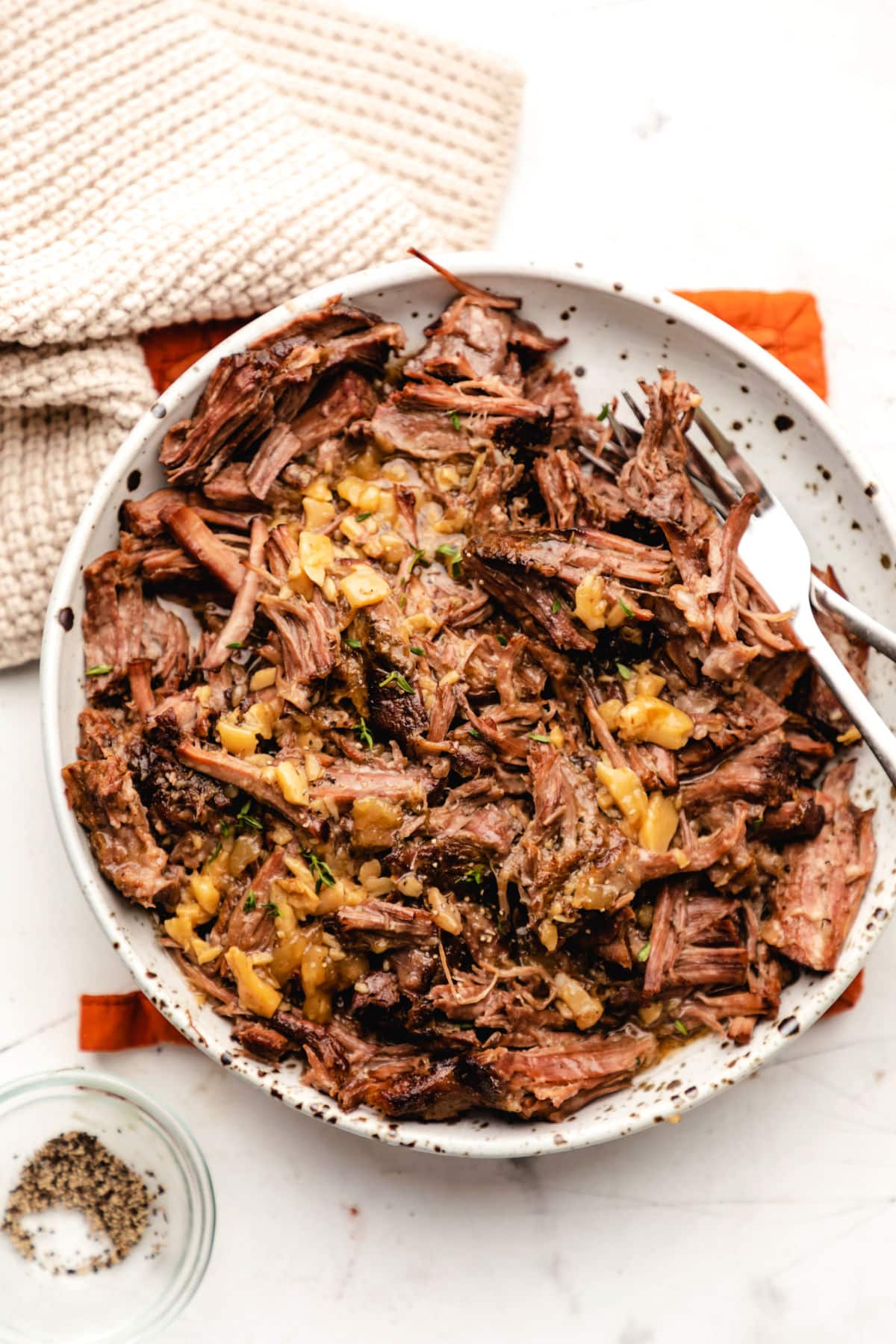 A plate of crock pot garlic pot roast on an orange pot holder. 