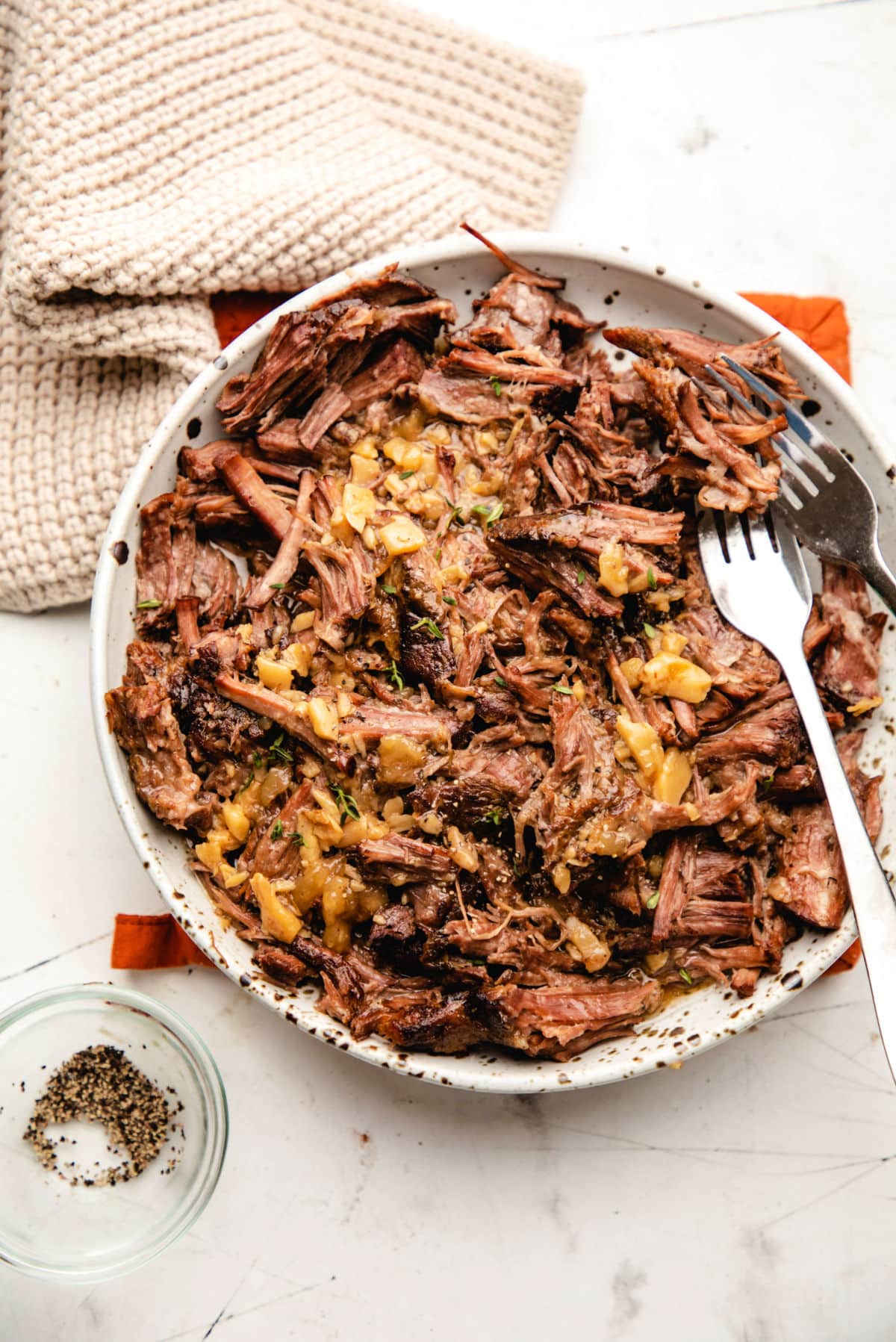 A plate of crock pot garlic pot roast with two forks in it.