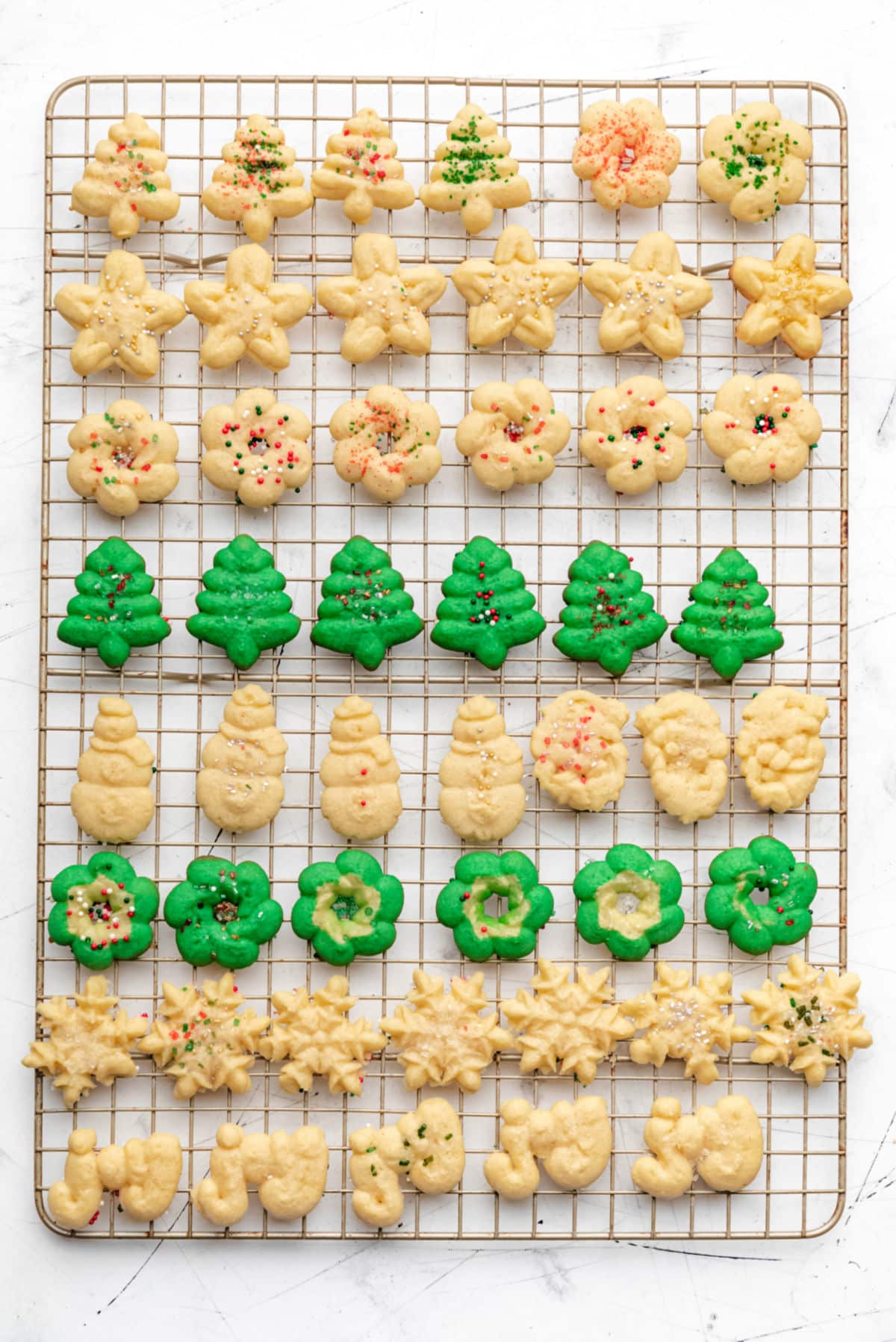 Rows of spritz cookies on a wire cooling rack. 