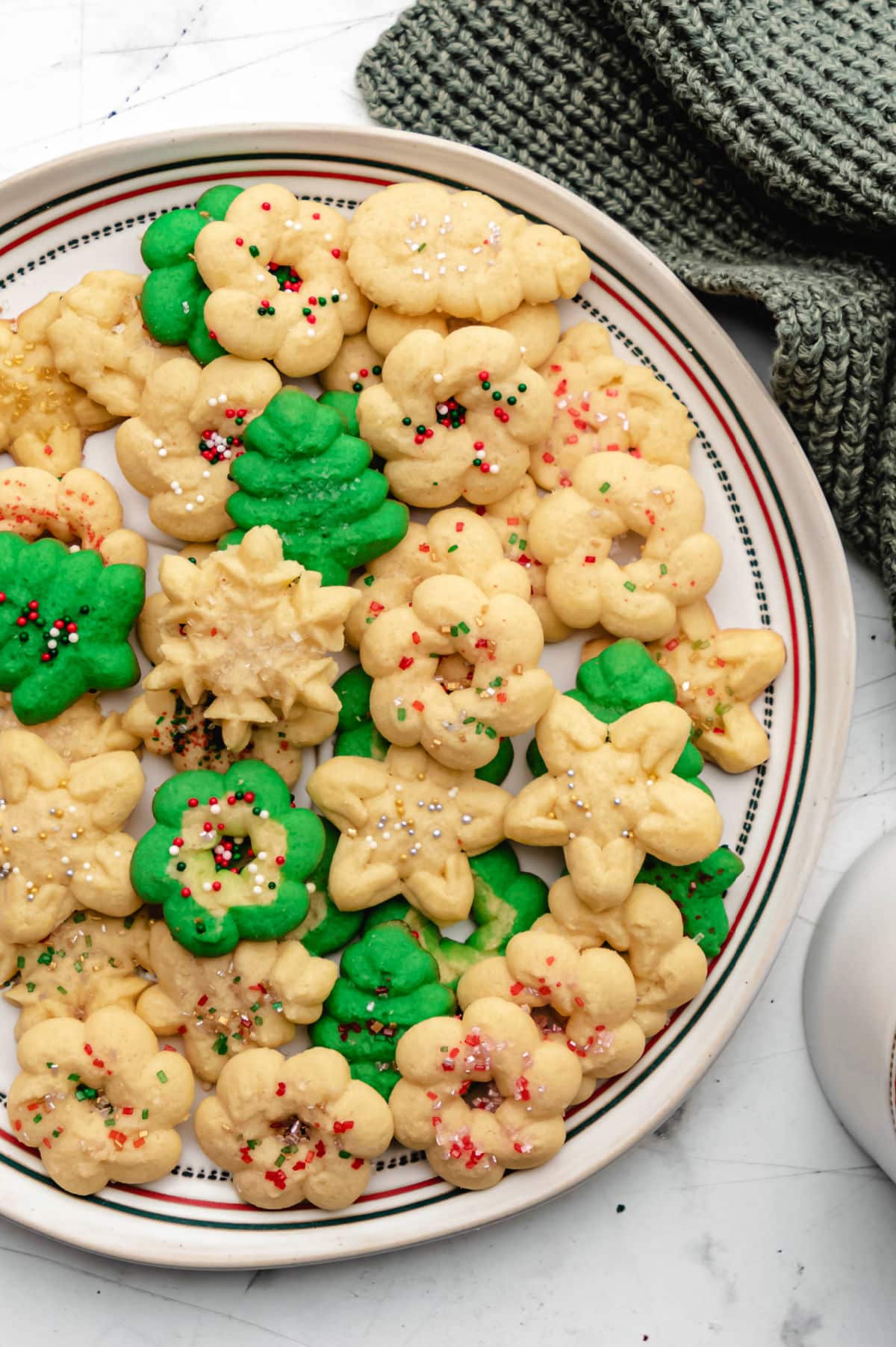 A plate of spritz cookies next to a green knit napkin.