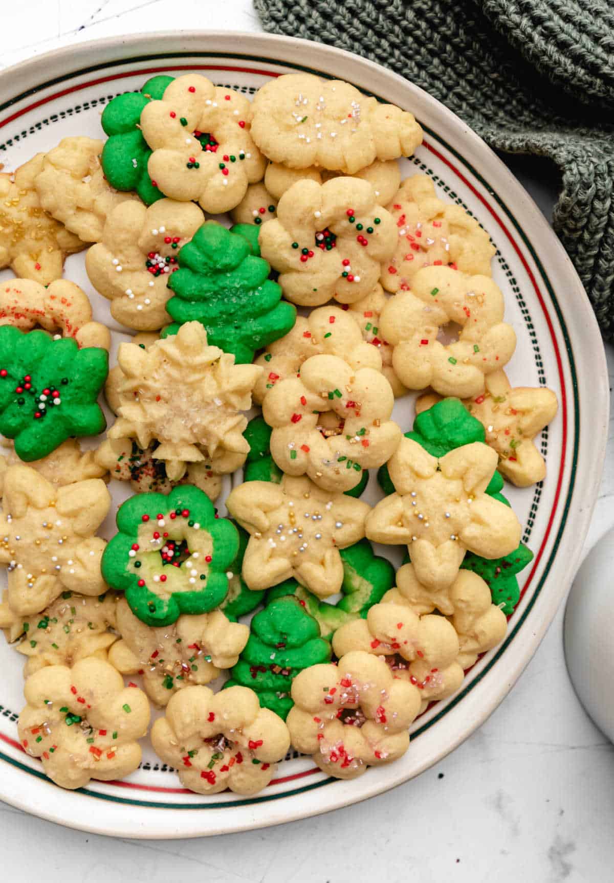 A white plate of spritz cookies next to a white mug. 