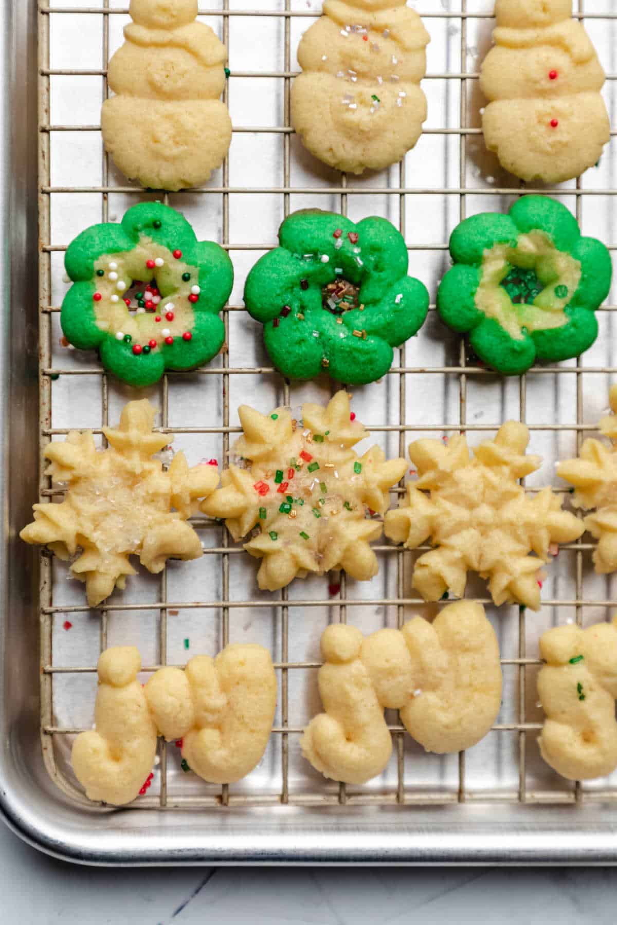 Baked spritz cookies on a wire cooling rack. 