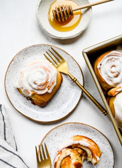 A honey bun on a plate with a gold fork.