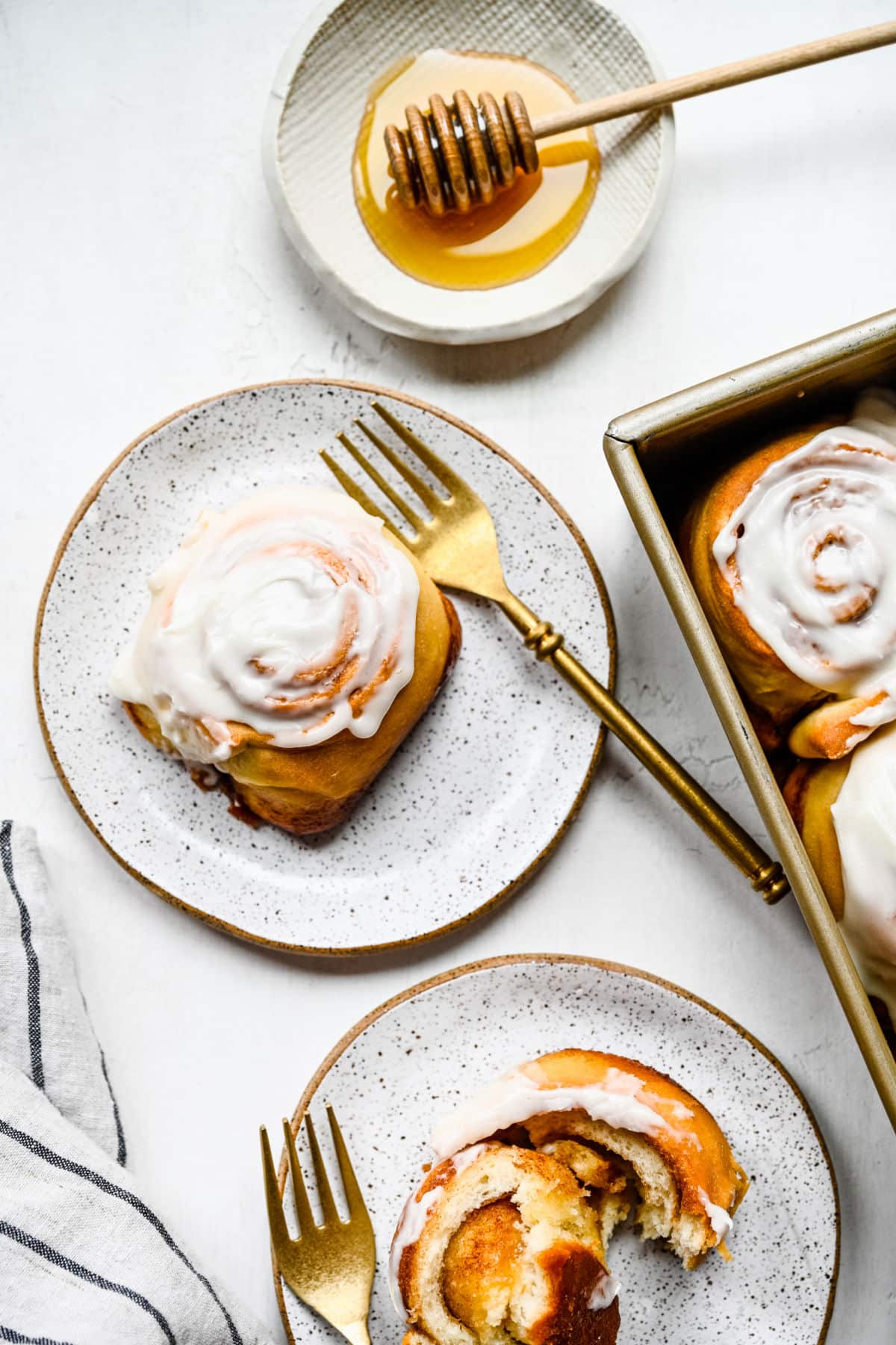 A honey bun on a plate with a gold fork.