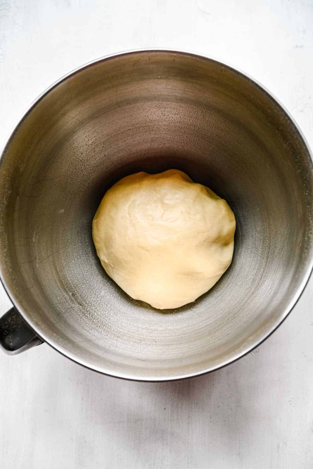 Honey bun roll dough in a silver mixing bowl. 