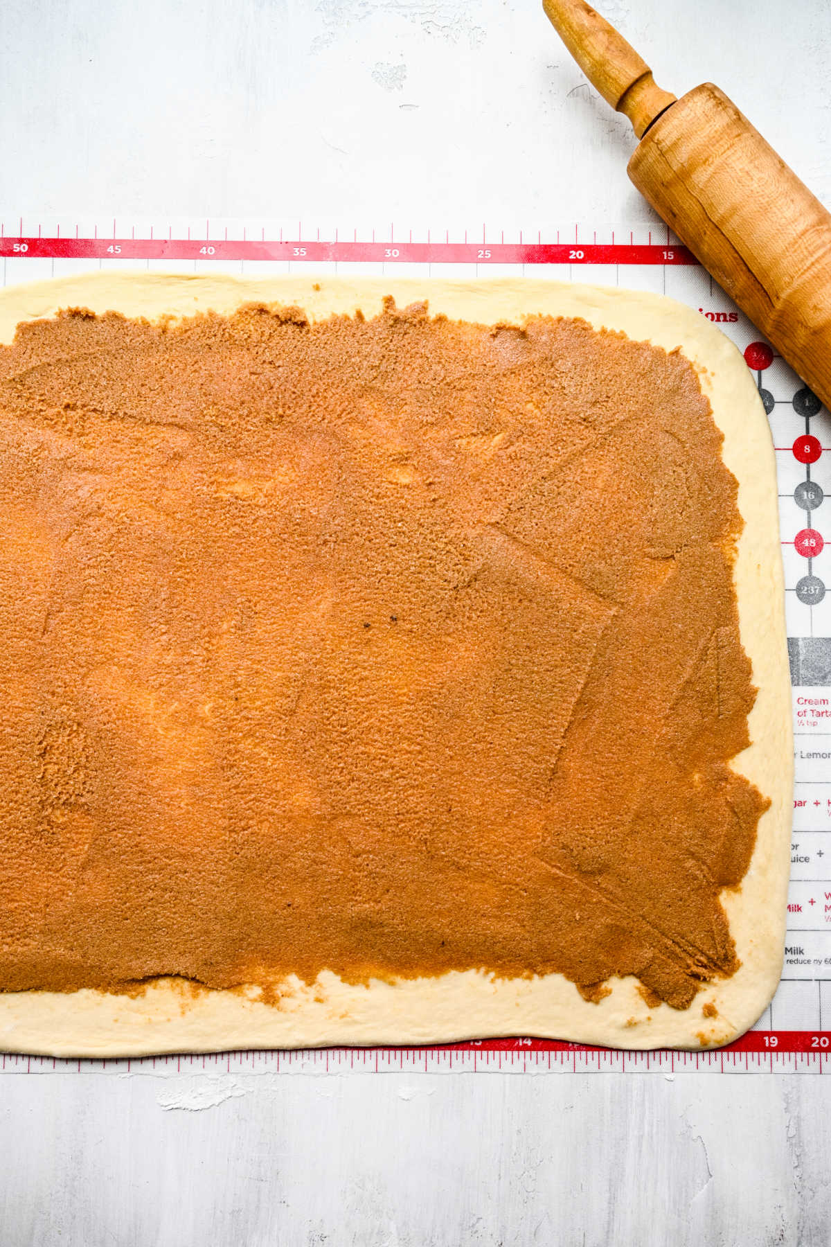 Filling on honey bun dough next to a rolling pin.