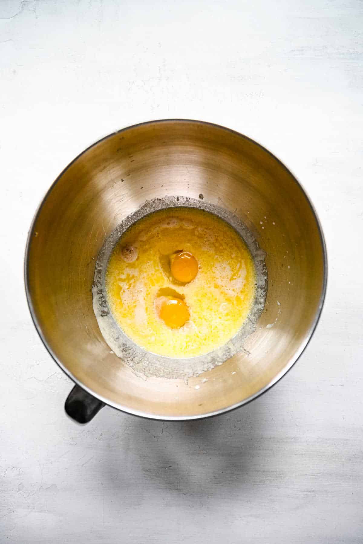 Butter milk and eggs added to sugar and yeast mixture in a mixing bowl. 