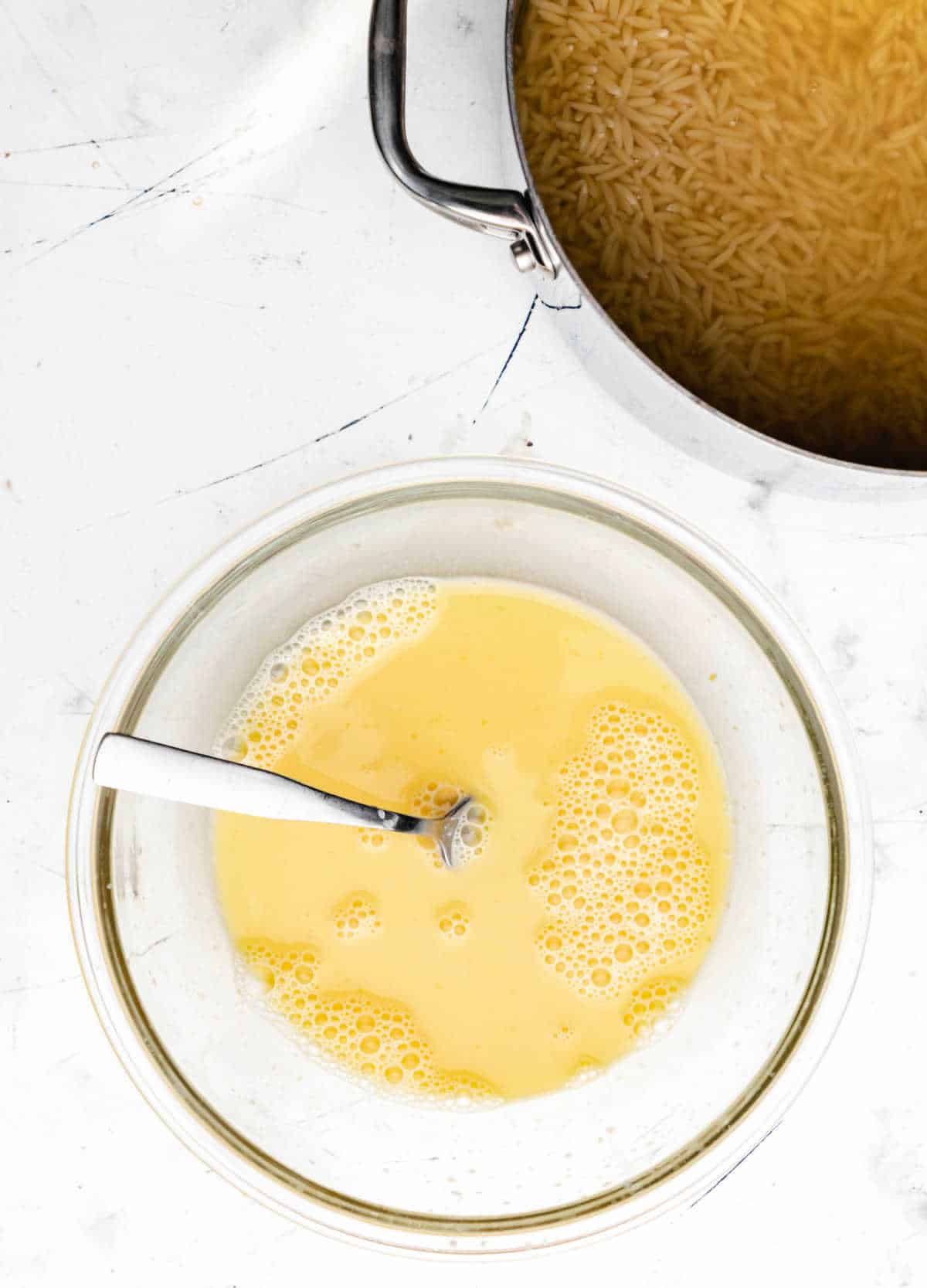 Egg and chicken broth mixed together in a glass bowl.