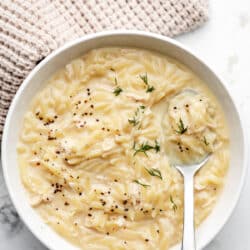 A bowl of avgolemono topped with fresh dill and black pepper.