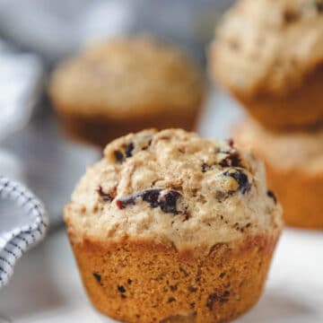 A bran muffin in front of three other bran muffins.