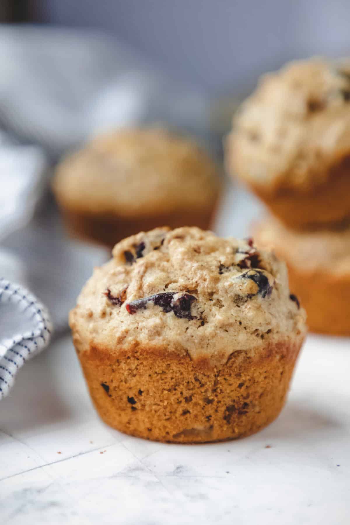 A bran muffin in front of three other bran muffins.