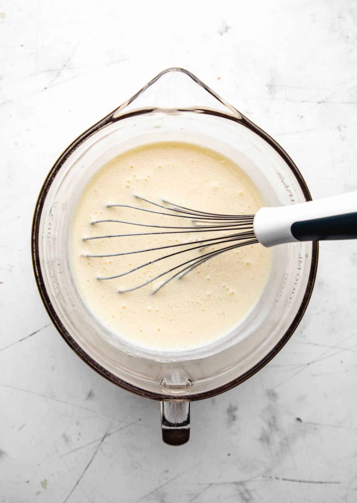 Buttermilk and eggs whisked together in a glass mixing bowl.