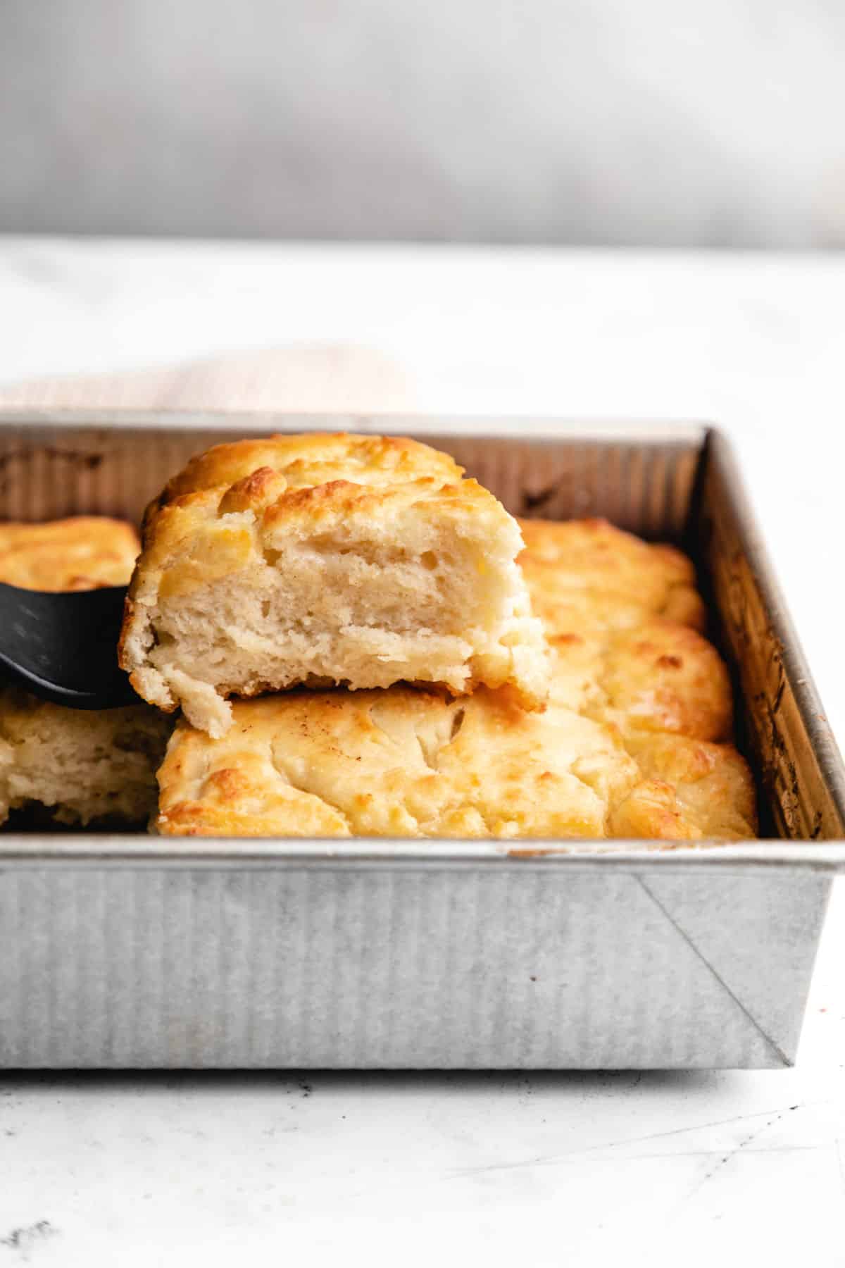 A butter swim biscuit on top of biscuits in a pan.