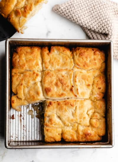 A pan of butter swim biscuits with one biscuit missing from the pan.