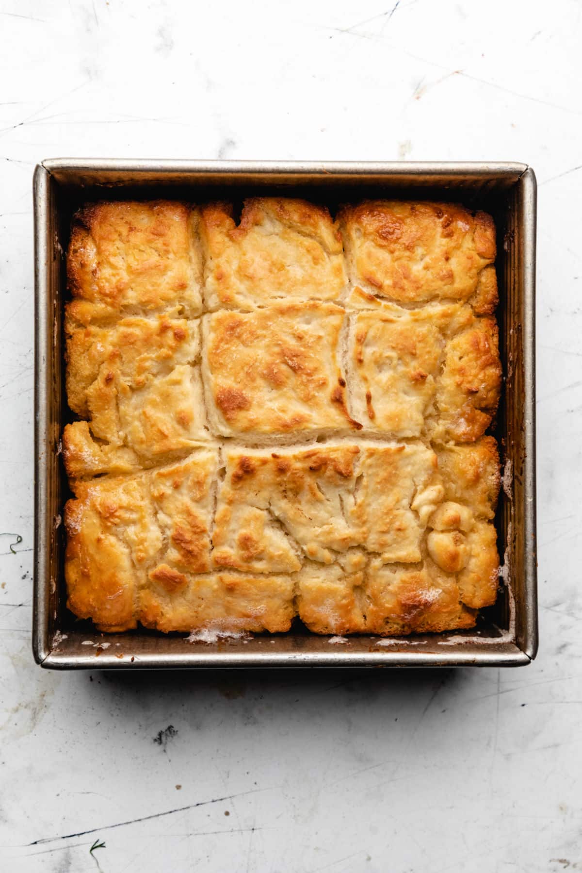 An 8 by 8 pan with baked butter swim biscuits in it. 