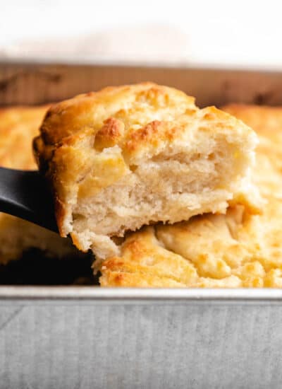 A spatula lifting up a butter swim biscuit from the pan.