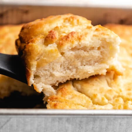 A spatula lifting up a butter swim biscuit from the pan.