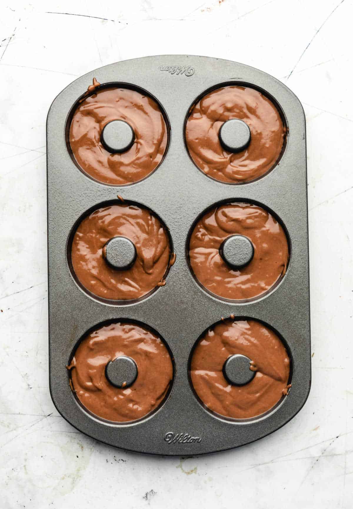 Chocolate buttermilk donut batter in a donut pan. 