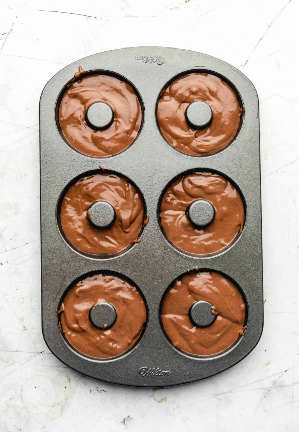 Chocolate buttermilk donut batter in a donut pan.
