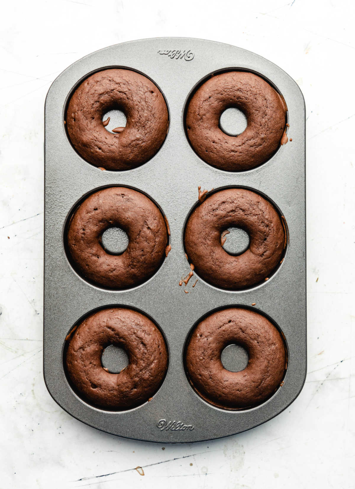 Baked chocolate buttermilk donuts in a donut pan. 