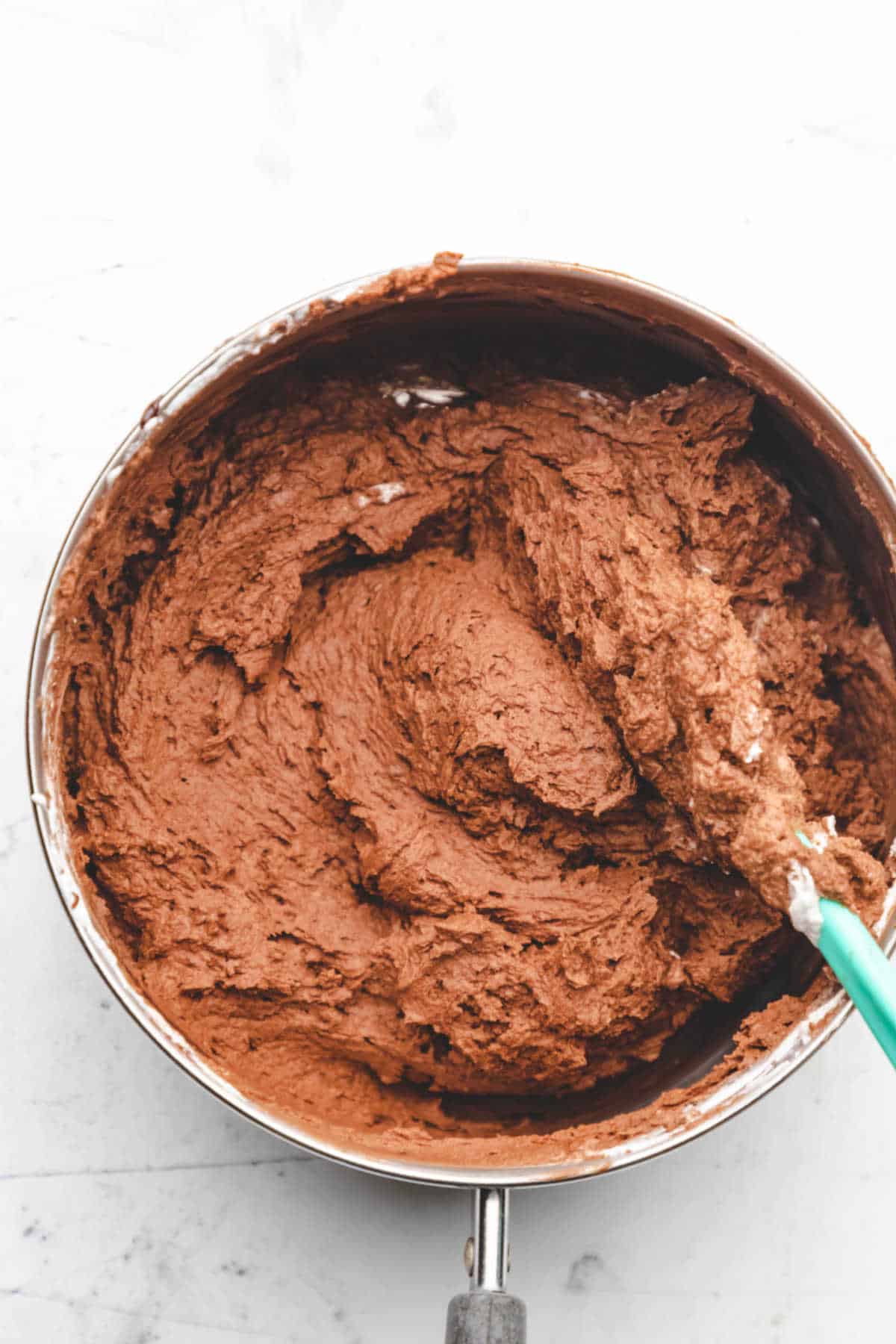 A spatula folding cooled chocolate and whipped cream together.