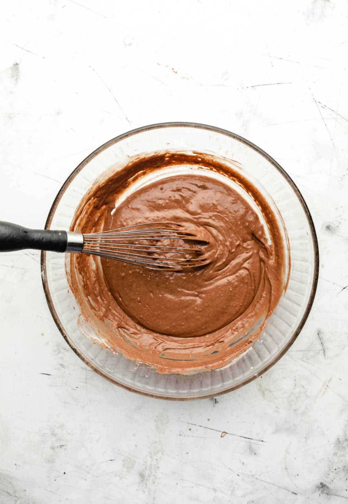 Chocolate buttermilk baked donut batter in a glass mixing bowl. 