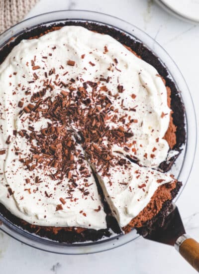 A cake server lifting a piece of chocolate mousse pie out of the pie.