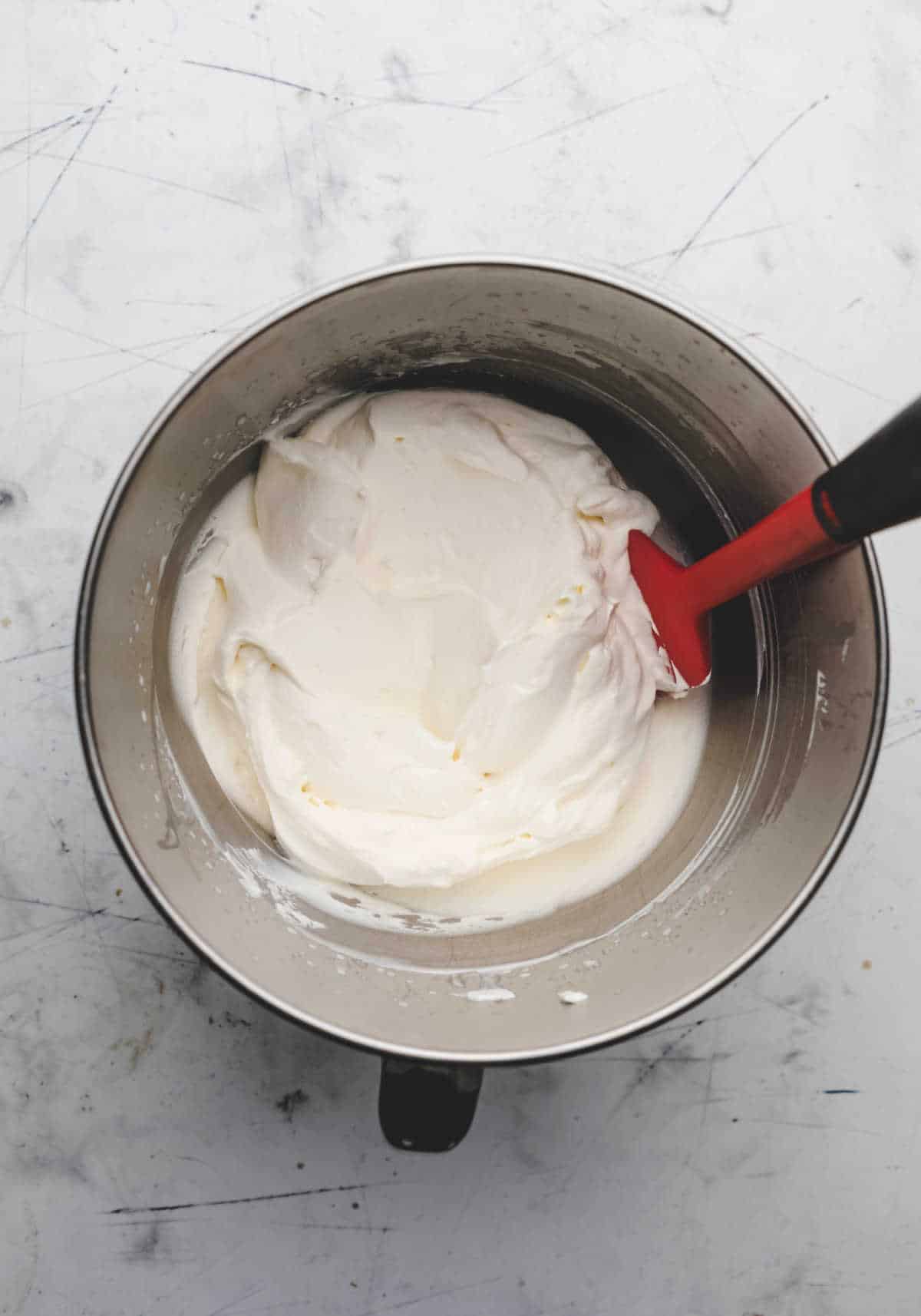 Whipped cream in a silver mixing bowl. 