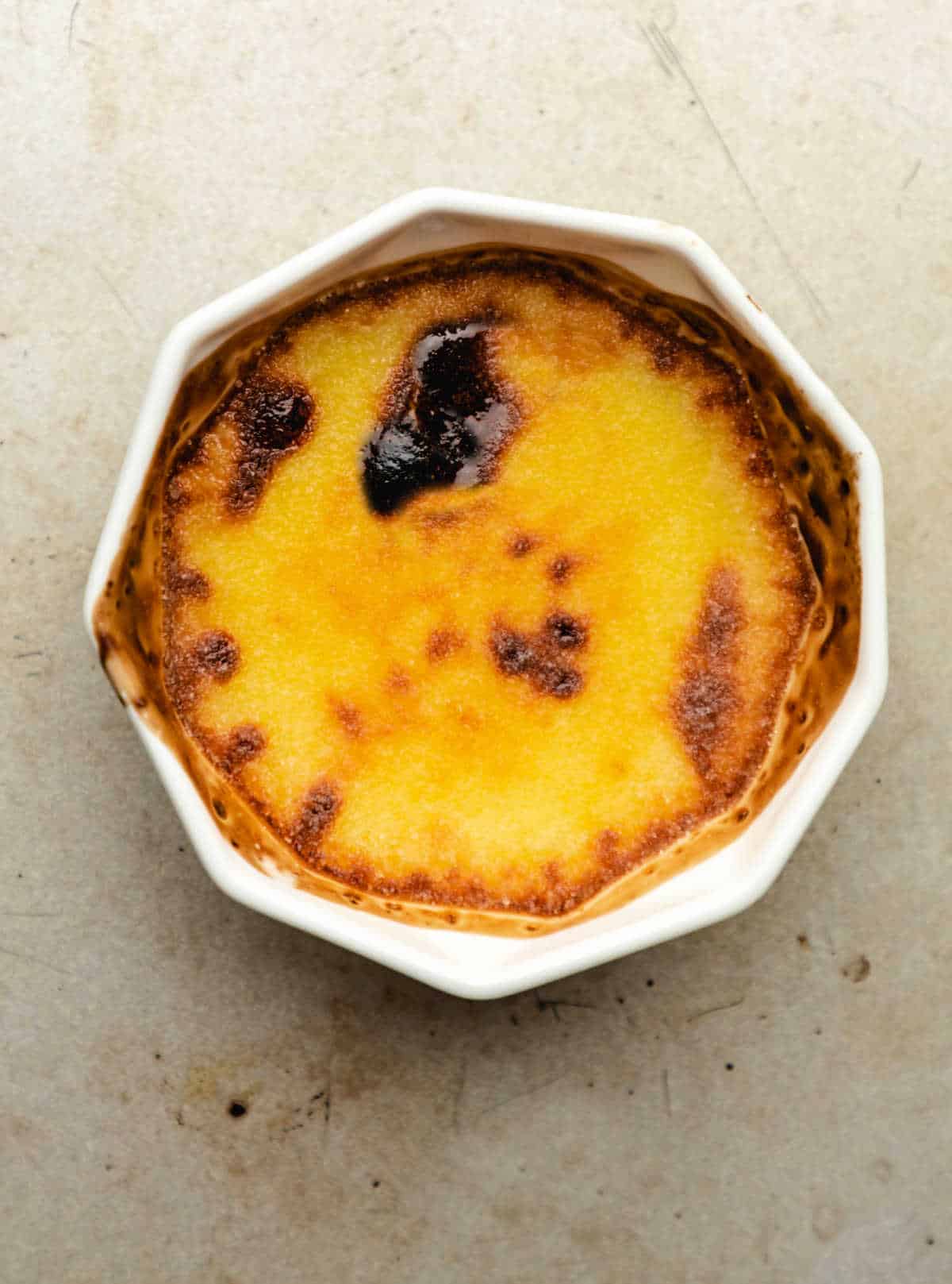 A dish of creme bruhlee on a baking sheet pan. 