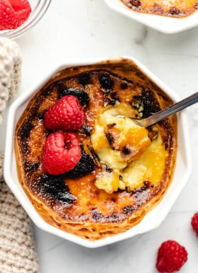 A spoon scooping up a bite of creme bruhlee from a ramekin.